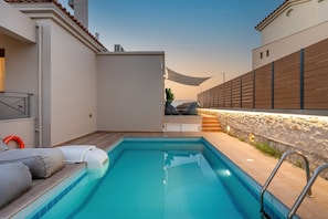 Uma piscina com espreguiçadeira e parede de pedra.