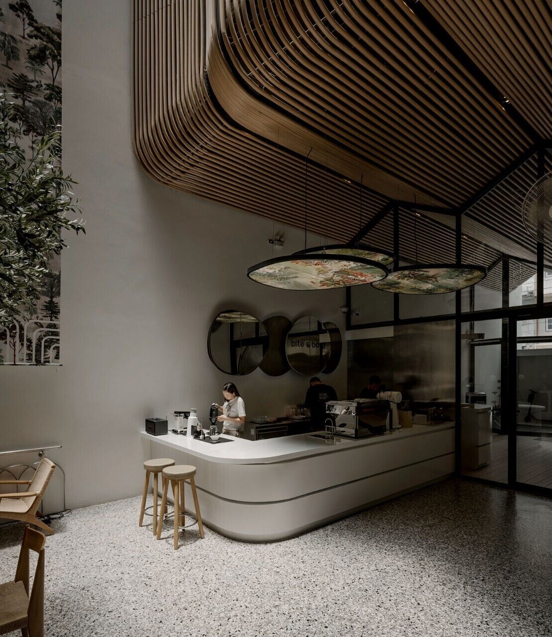 Un intérieur moderne avec un comptoir incurvé, des tabourets et un plafond orné de lambris en bois.
