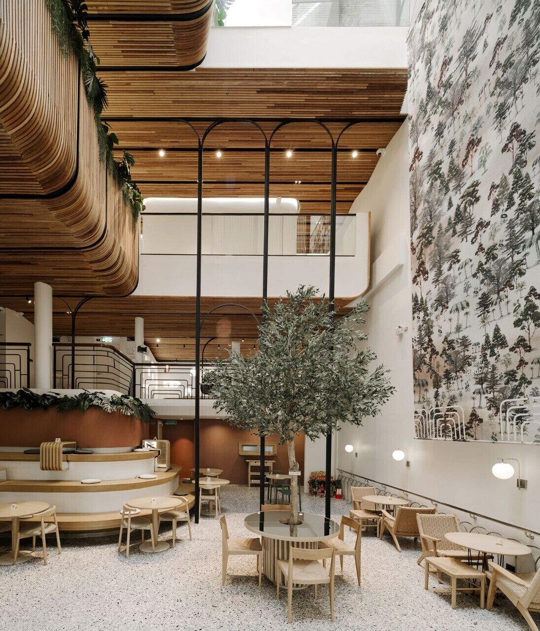 Een modern interieur met een centraal zithoek, een trap en een wand met een behang in natuurthema.