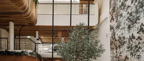 Een modern interieur met een centraal zithoek, een trap en een wand met een behang in natuurthema.