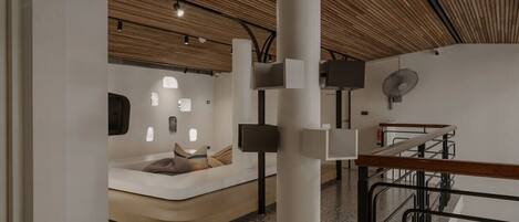 Un intérieur moderne avec un plafond en bois, une colonne centrale et un espace détente agrémenté de coussins.
