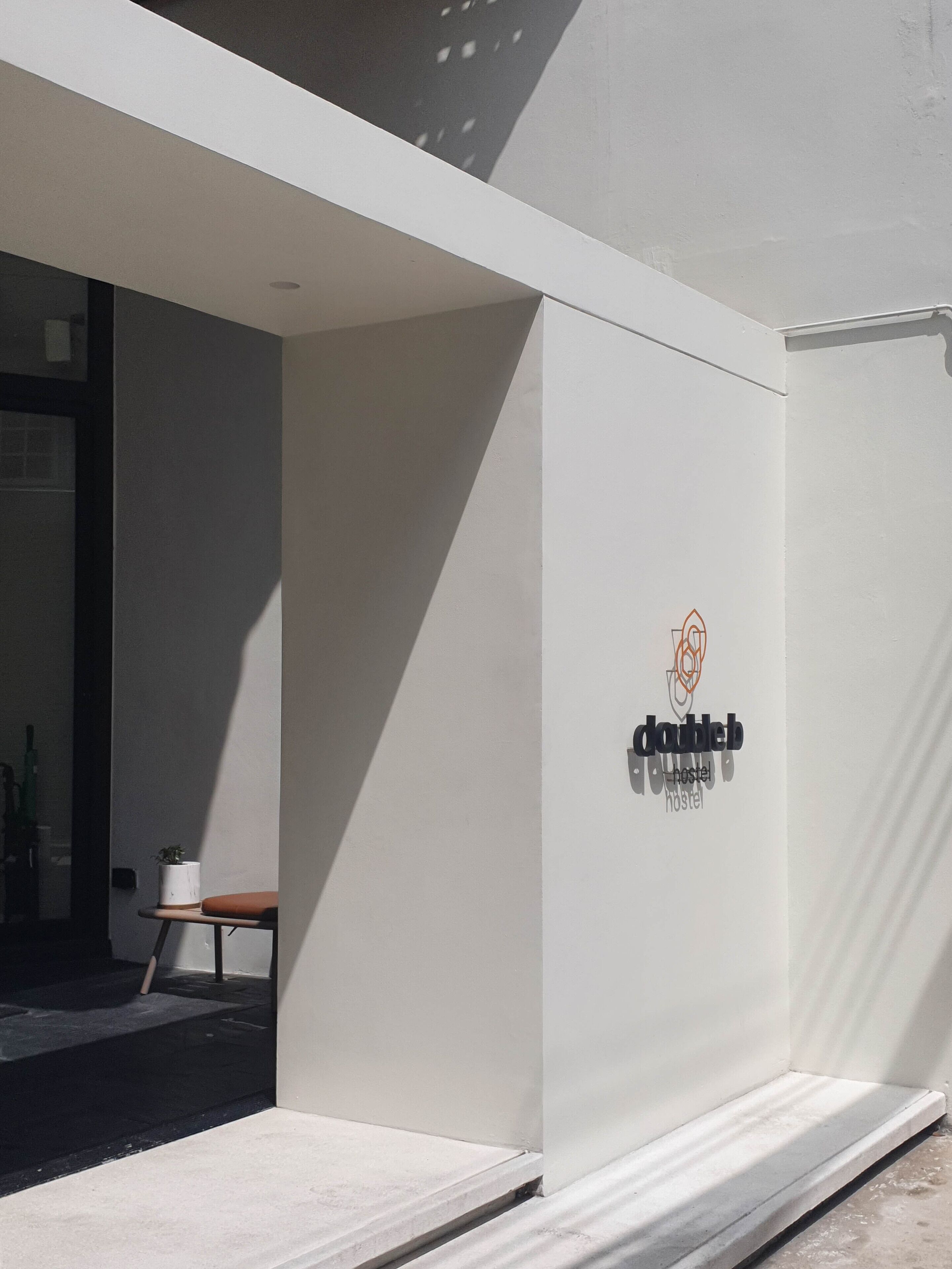 A modern hostel exterior with a clean, minimalist design, featuring a logo and the name 'dableb hostel' on the wall.