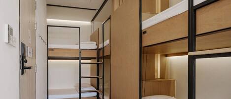 A modern hotel room with bunk beds, wooden flooring, and a built-in wardrobe.