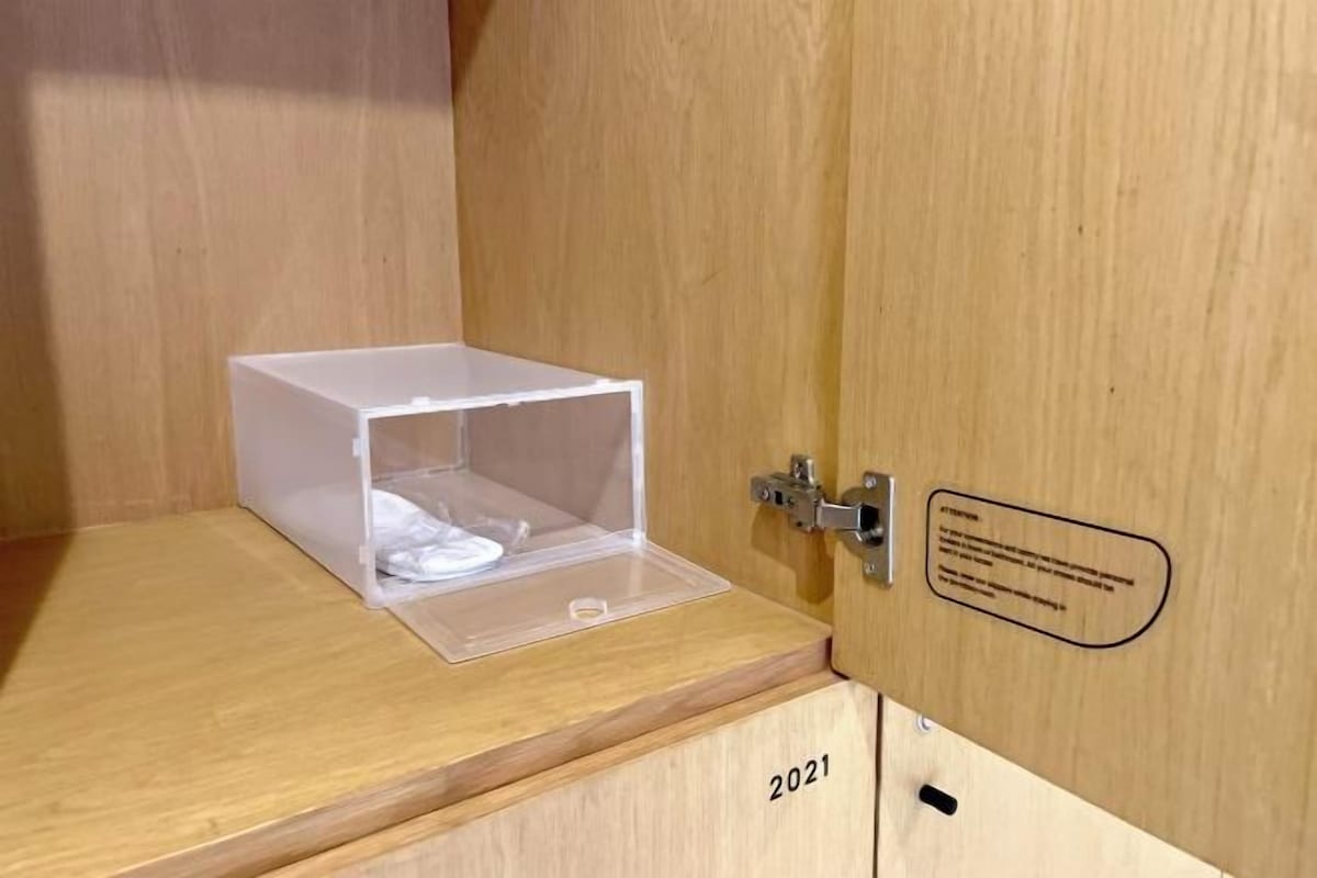 A wooden cabinet with a transparent plastic container on top.