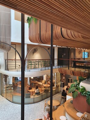 A multi-level indoor space with seating areas, a staircase, and a large plant. - Double B Hostel (Bangkok)