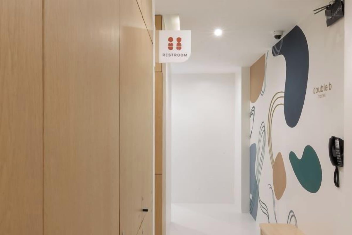 A hallway with a sign indicating a restroom, a phone, and abstract wall art.