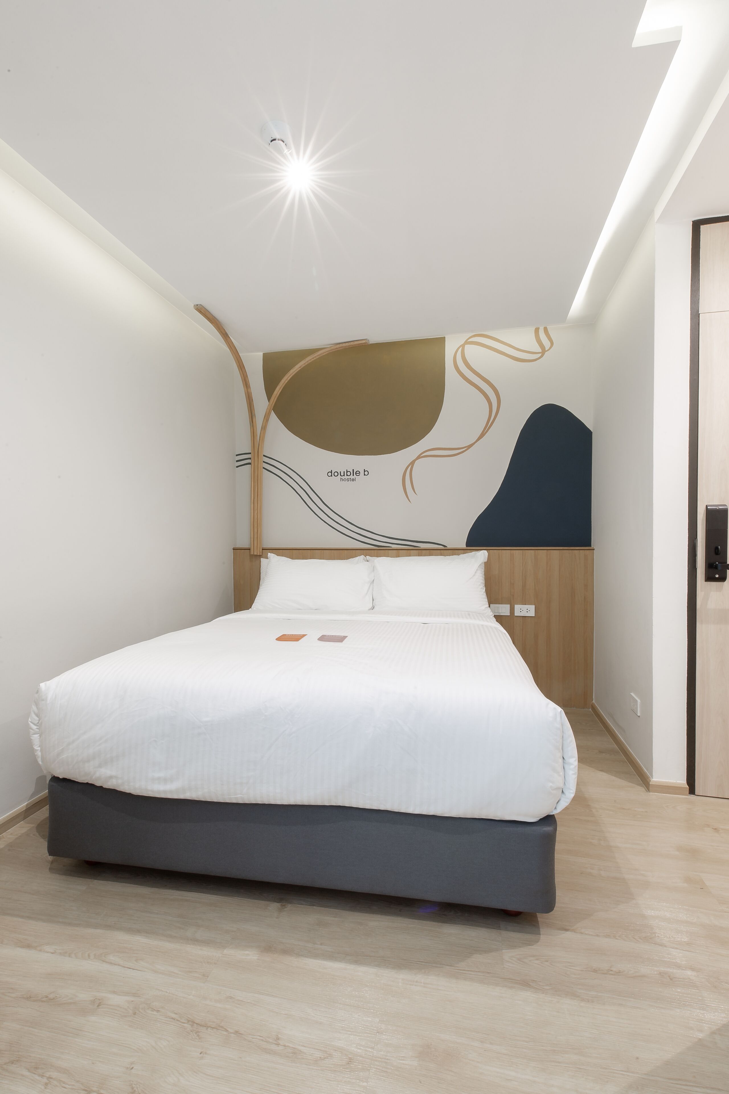 Ein modernes Hotelzimmer mit Bett, Wandbild und Deckenleuchte.