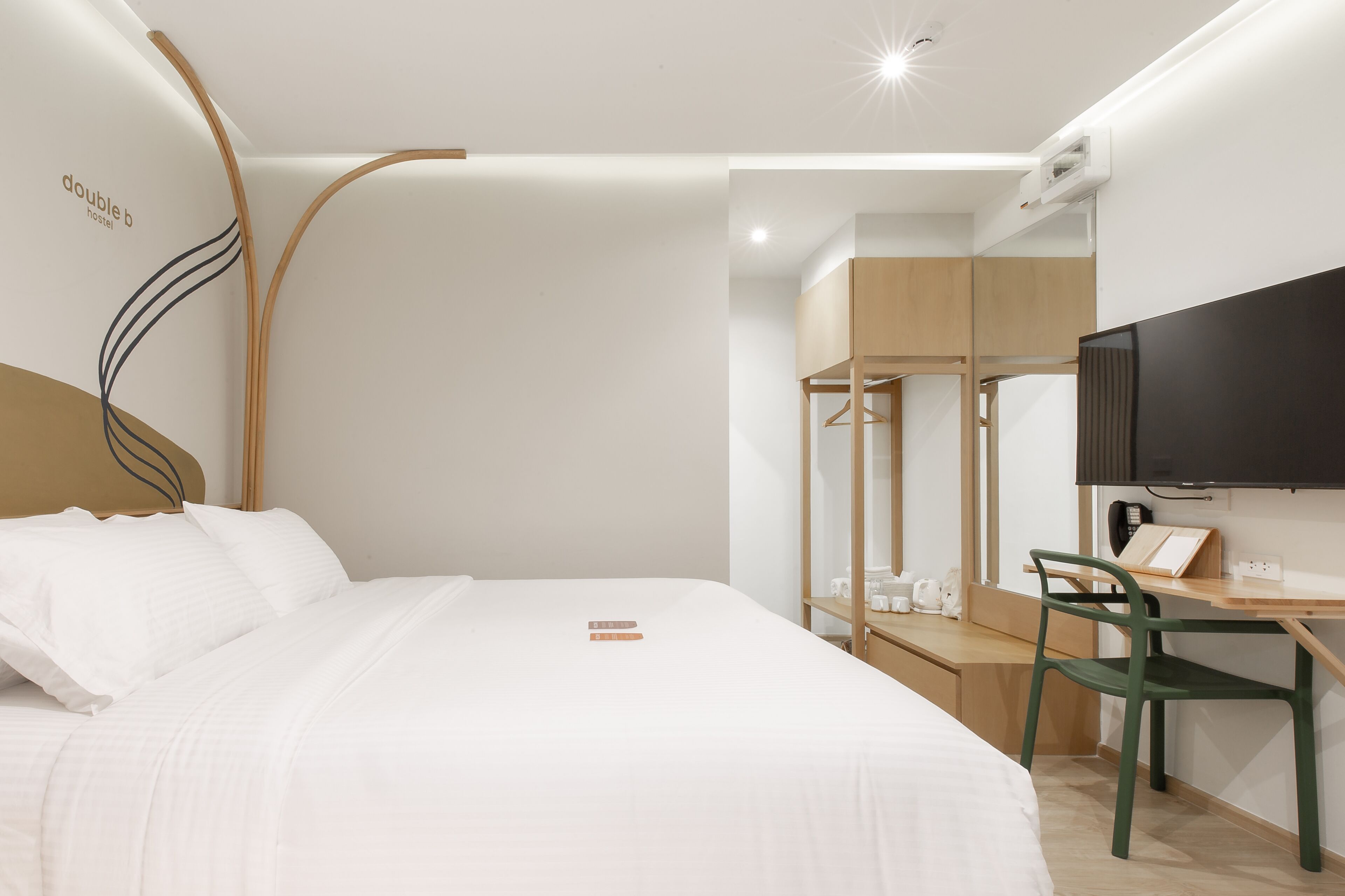 A modern hotel room with a bed, a desk, a chair, a television, and a bunk bed.