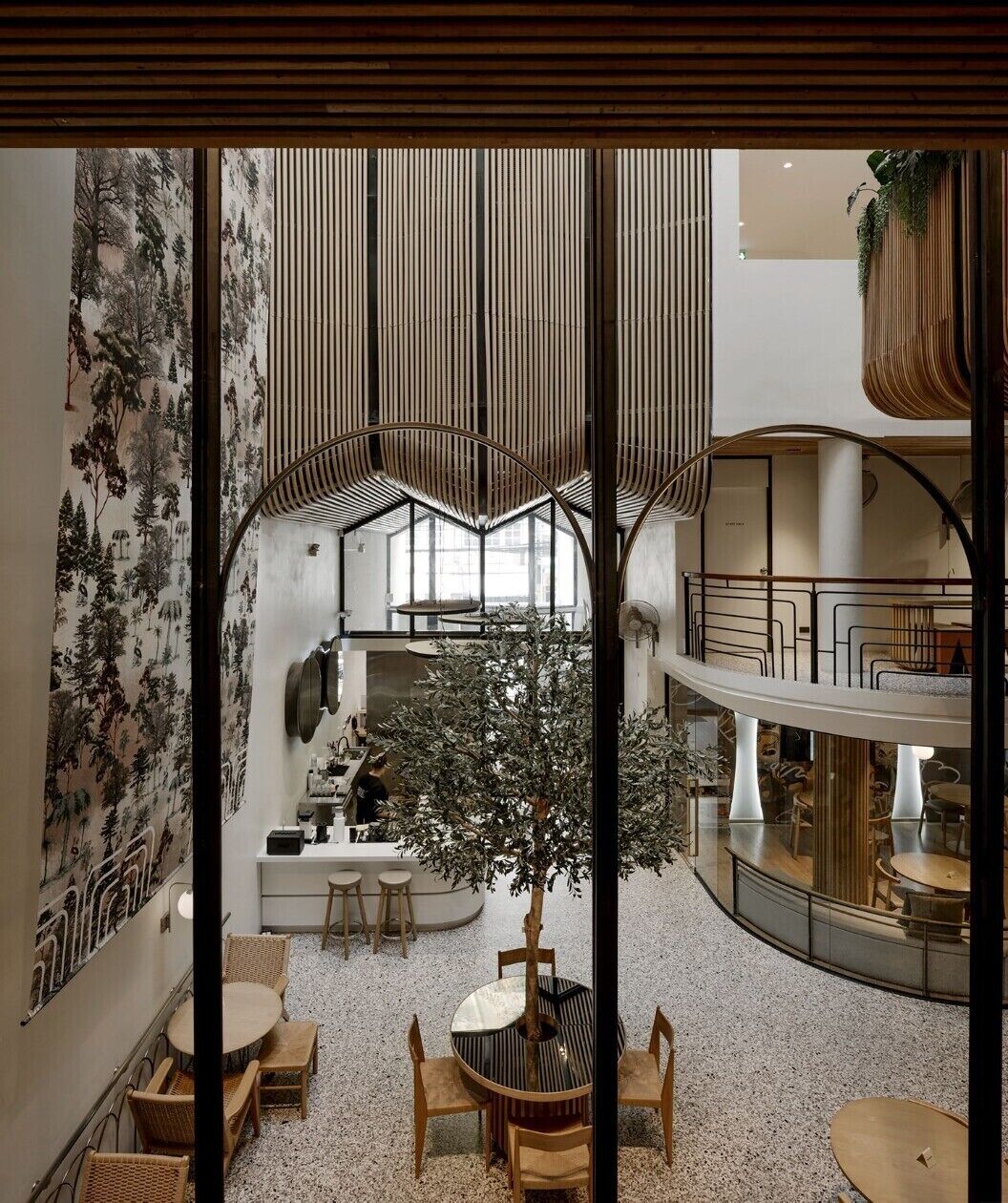 Un intérieur moderne avec un arbre central, des espaces de détente et une mezzanine.