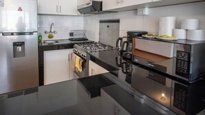 A modern kitchen with stainless steel appliances, white cabinets, and a black countertop. - Spacious 4 Bedroom Full Apartment, a few Minutes From the Main Square (Cusco)