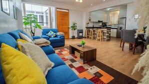 A modern living room with a blue sofa, a coffee table, and a colorful rug. - Spacious 4 Bedroom Full Apartment, a few Minutes From the Main Square (Cusco)