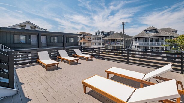 A wooden deck with lounge chairs and a staircase leading to an upper level. - Surf Club - King Bed, 2 Mins to OC Beach & POOL (Ocean City)