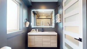 A modern bathroom with a large mirror, a white sink, and a wooden vanity. - Surf Club - King Bed, 2 Mins to OC Beach & POOL (Ocean City)