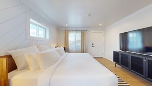 Habitación de hotel moderna con una cama grande, televisión y vistas a la ciudad a través de la ventana.