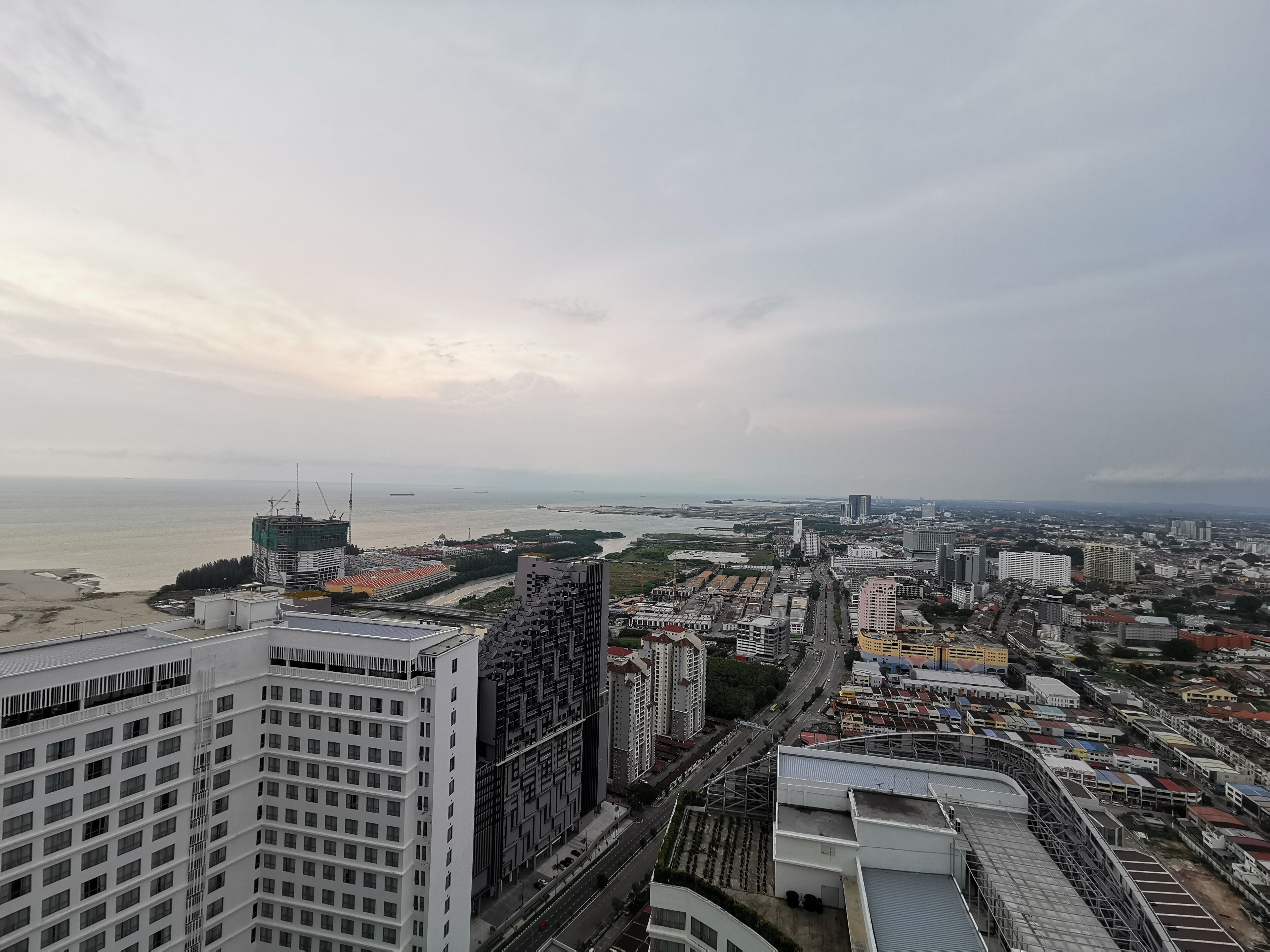A high-rise building with a view of a coastal cityscape, including a beach and a river.