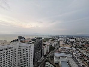 Un edificio alto con vistas a una ciudad costera, que incluye una playa y un río.