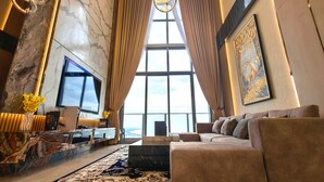 A spacious living room with a large sofa, a flat-screen TV, and a marble wall. - Attic Home Melaka Silverscape Residence (Malacca City)