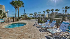 A pool area with lounge chairs and a small pool, surrounded by palm trees and a rocky landscape. - Townhouse style condo in beautiful resort across the street from Gulf of Mexico! (Panama City)