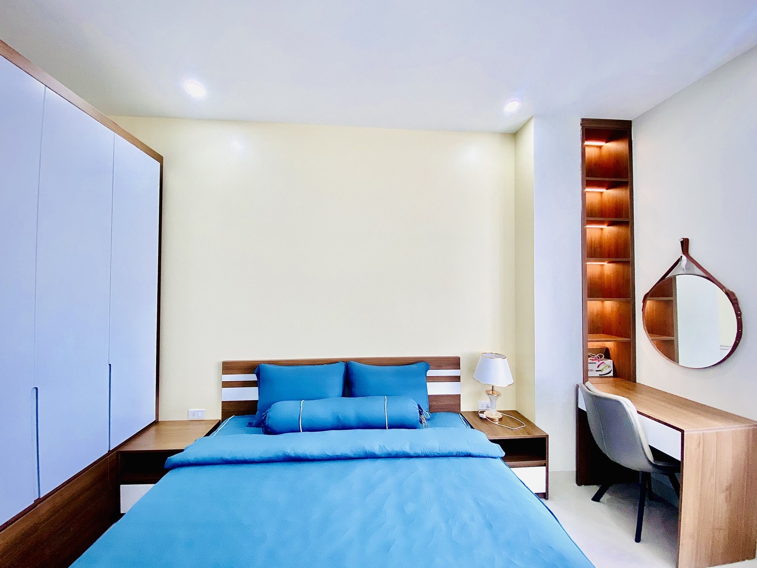 Un dormitorio con cama, mesita de noche, lámpara, escritorio, silla y armario.