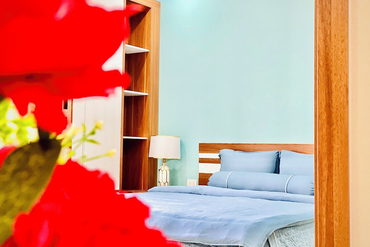 A bedroom with a bed, a nightstand, a lamp, and a wooden wardrobe.