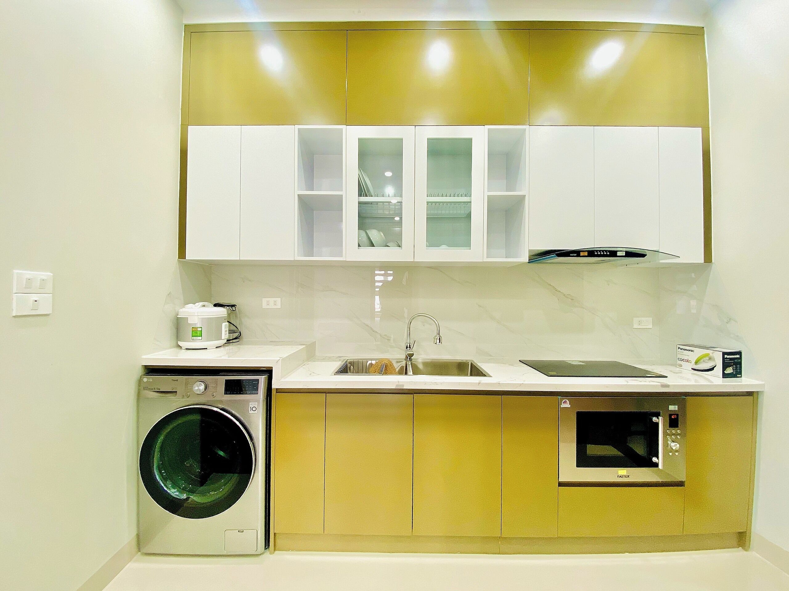 A compact kitchen with a washing machine, a microwave, and a sink.