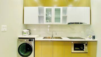 A compact kitchen with a washing machine, a microwave, and a sink.