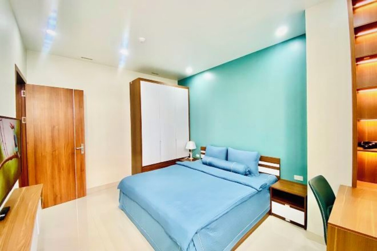 A modern bedroom with a bed, bedside tables, a desk, and a chair.