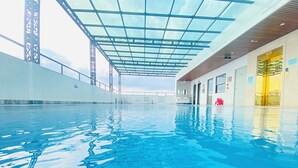 Una piscina interior con techo de cristal, agua transparente y diseño arquitectónico moderno.