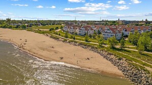 Una zona costera con una playa de arena, una hilera de casas y un cielo despejado.