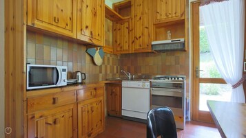 Una cocina con gabinetes de madera, microondas, cafetera, lavavajillas y estufa.