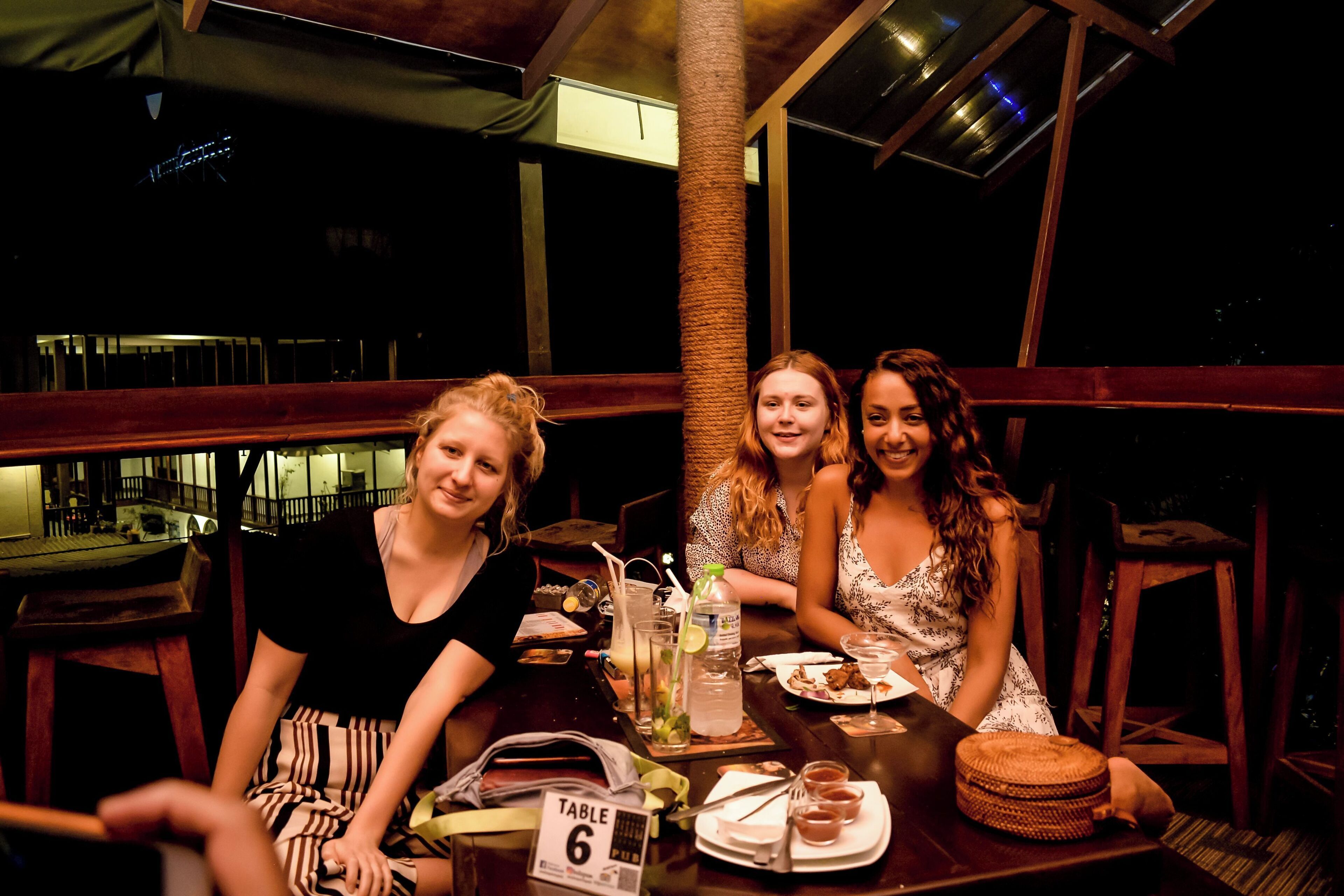 Three people seated at a table with a table number sign, a menu, and a drink.