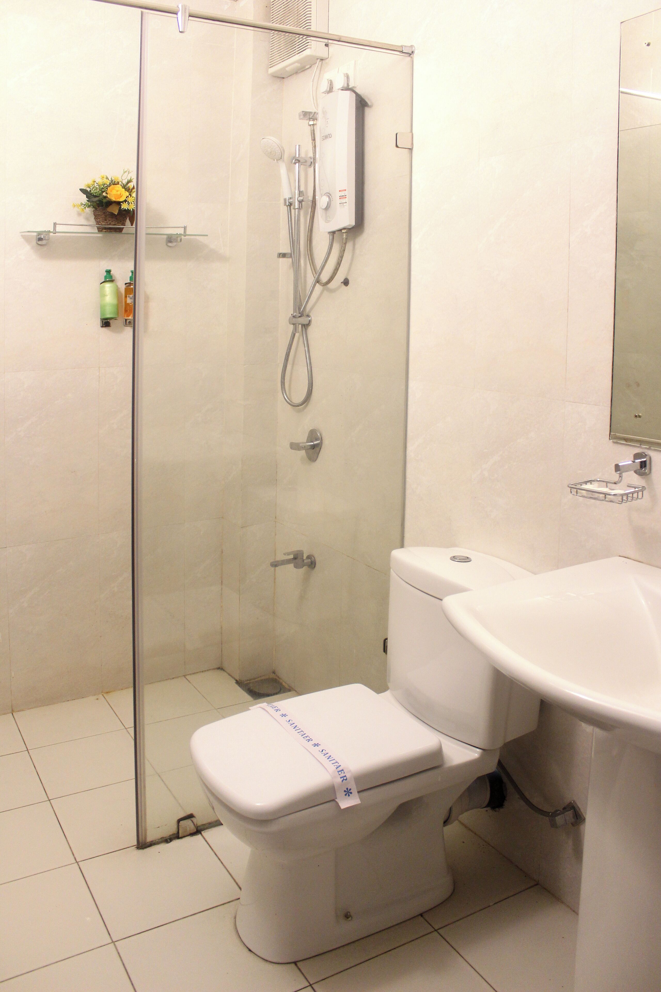 A bathroom with a glass-enclosed shower, a toilet, and a sink.