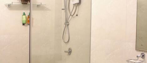 A bathroom with a glass-enclosed shower, a toilet, and a sink.