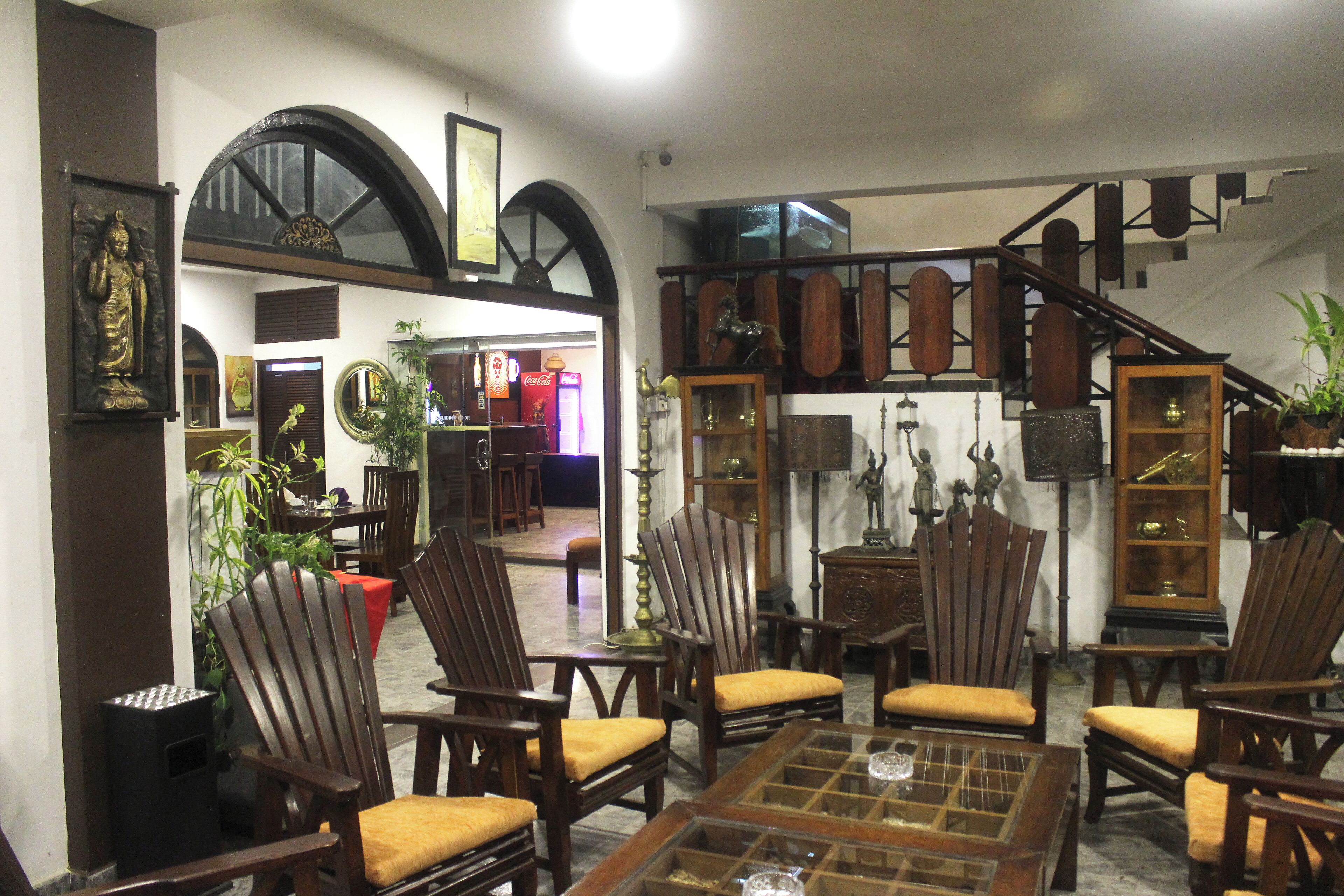 Una habitación con muebles de madera, incluyendo sillas y una mesa, y una escalera al fondo.