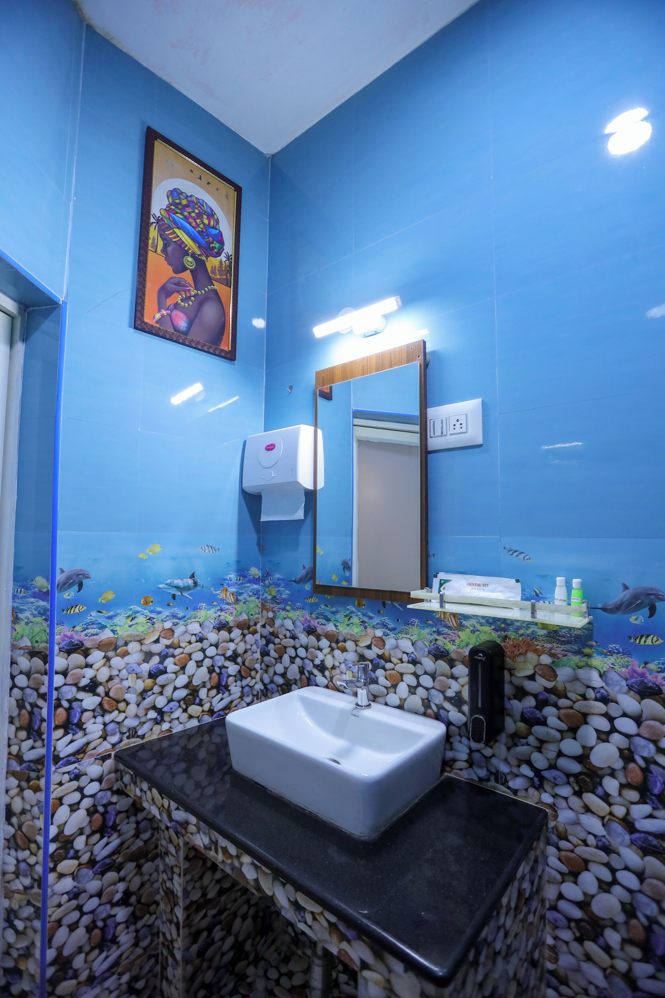 Une salle de bain avec un mur bleu, un tableau encadré, un lavabo, un miroir et un aquarium.