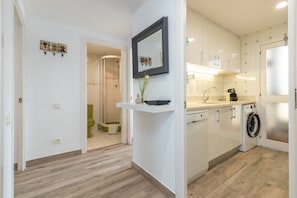 Una cocina moderna con armarios blancos, lavadora integrada y un lavamanos pequeño.