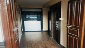 Un pasillo con puertas de madera y vistas a una habitación con un ventanal grande.