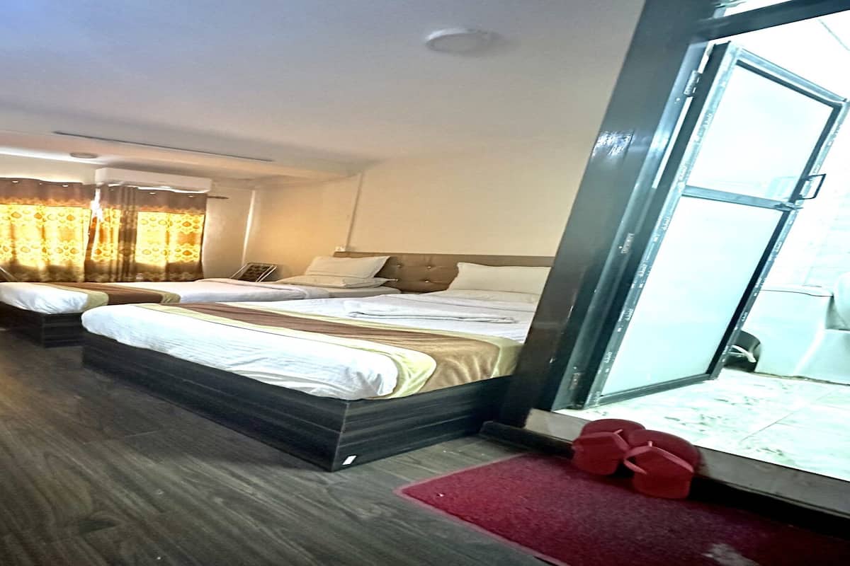 Hotellihuone, jossa on kaksi sänkyä, punainen matto ja ikkuna, jossa on verhot.