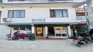 Un edificio de dos plantas con una tienda en la planta baja y una motocicleta roja estacionada frente.