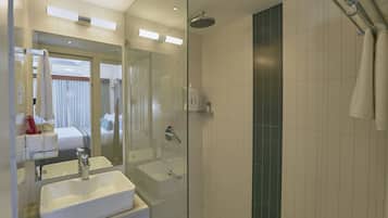 A modern bathroom with a glass-enclosed shower, a large mirror, and a white sink.