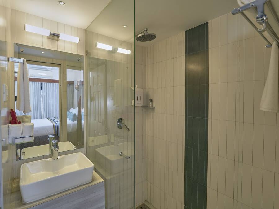A modern bathroom with a glass-enclosed shower, a large mirror, and a white sink.