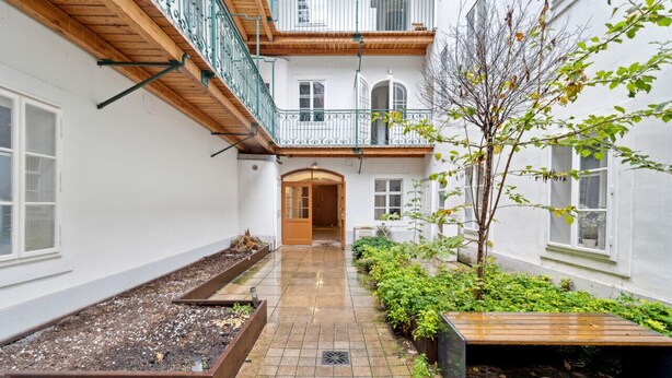 A courtyard with a wooden bench, a small tree, and raised garden beds. - Florian's apartments (Vienna)