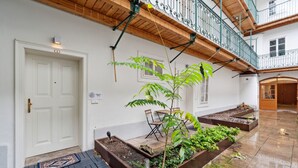 A courtyard with a white door, a bench, and planters with green plants. - Florian's apartments (Vienna)
