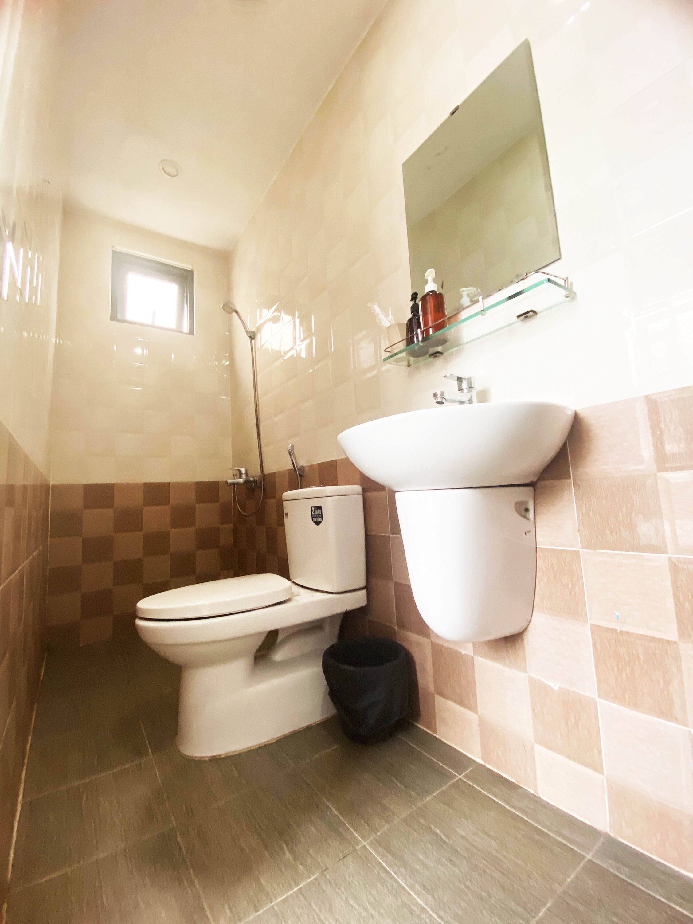 Un baño con inodoro, bidé y repisa de vidrio sobre el lavamanos.