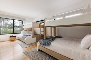 Una camera da letto moderna con letti a castello, un comodino e un'ampia finestra.