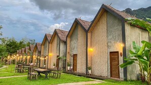 A row of wooden buildings with thatched roofs, each with a door and a small porch area.