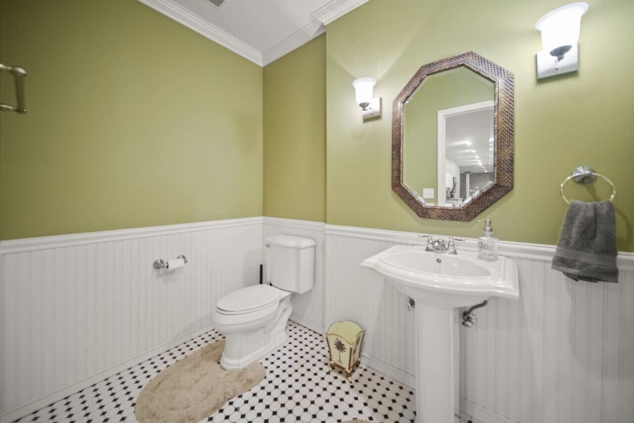 A bathroom with a toilet, sink, and mirror.