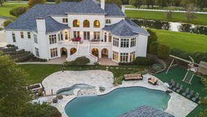 Una amplia casa de dos pisos con piscina, mobiliario exterior y un césped bien cuidado.