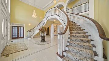 A grand staircase with white balustrades and floral carpeted steps leading to an upper level.