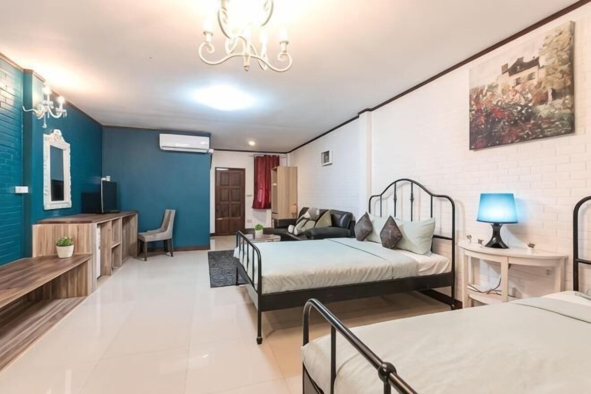 Un dormitorio con dos camas, un escritorio, una silla, una lámpara y un cuadro en la pared.